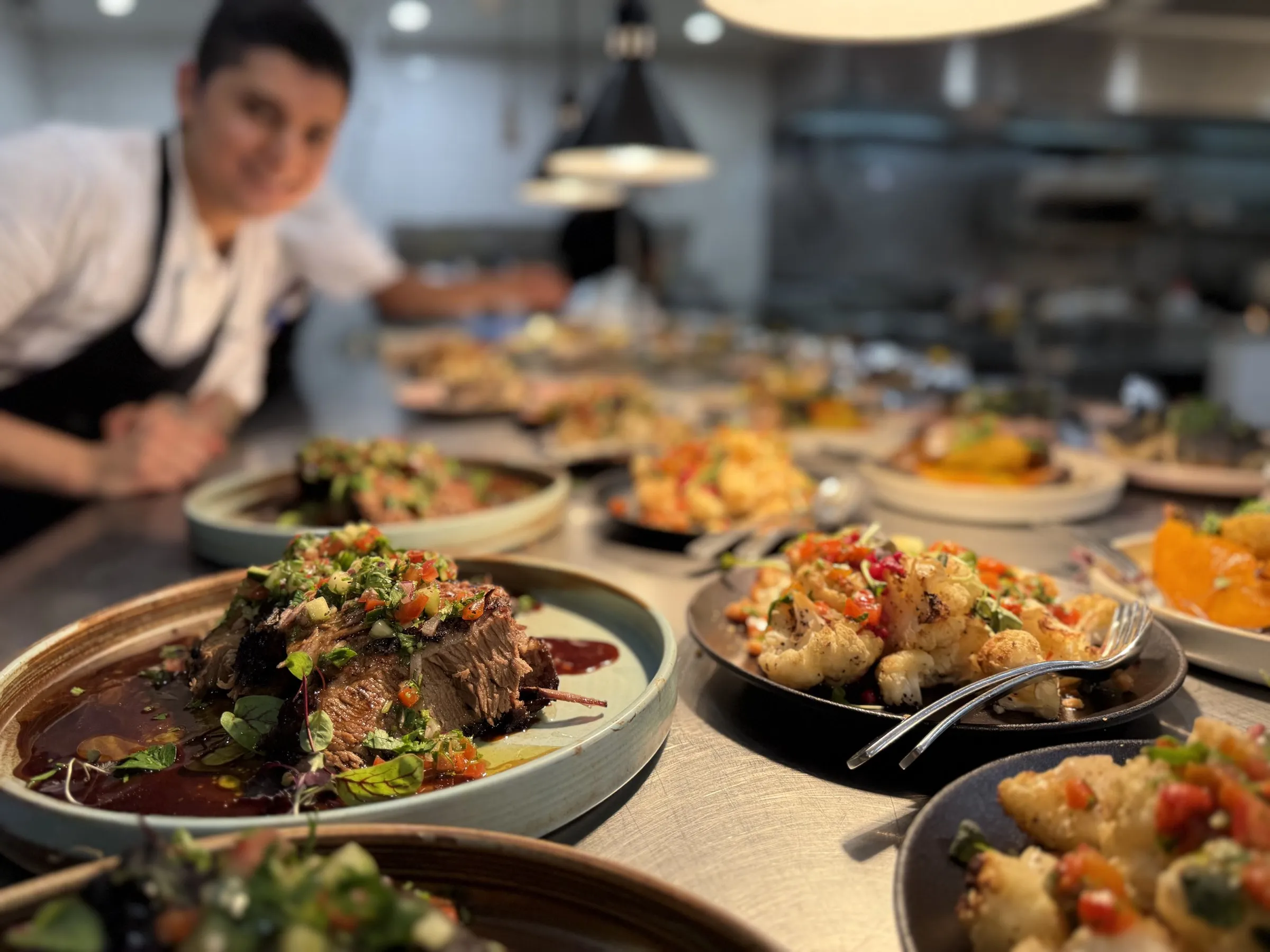 Plated dishes lined up on the pass with a chef behind them